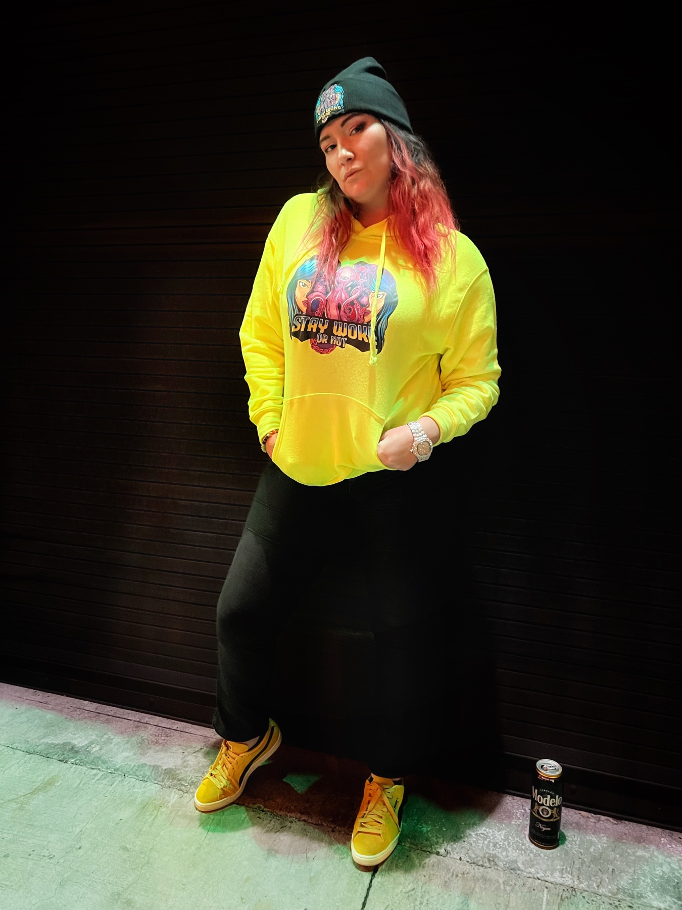 Dahlia wearing the neon yellow Stay Woke Or Not hoodie with a black beanie
